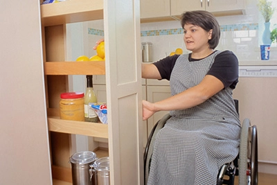 A woman in a wheelchair using an adapted kitchen